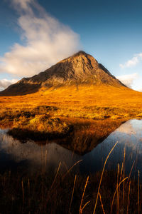 Stunning scottish mountain lit by warm autumn sunshine and reflected in a lochan