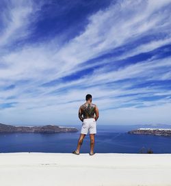 Rear view of man looking at sea against sky