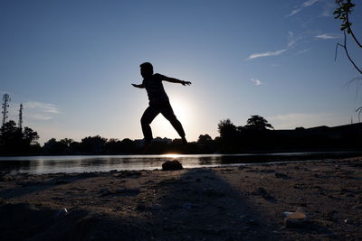 Side view of man jumping on beach against sky