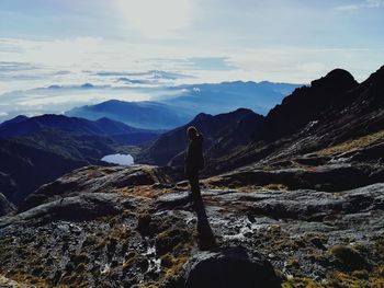 Side view of man standing on mountains against sky