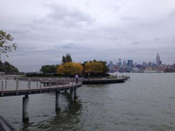 Bridge over river against cloudy sky