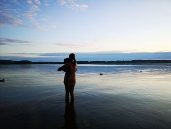 Rear view of woman standing on beach during sunset