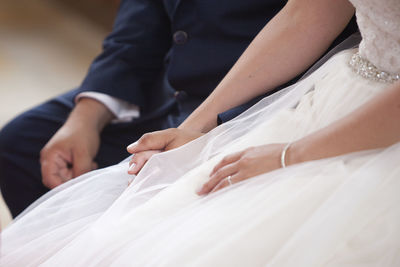 Midsection of bride holding wedding dress