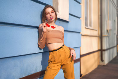 Portrait of beautiful woman standing by wall