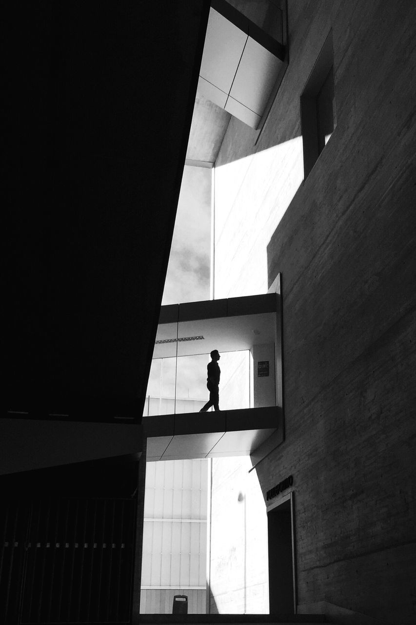 architecture, built structure, silhouette, indoors, standing, lifestyles, men, full length, building exterior, walking, building, rear view, low angle view, leisure activity, wall - building feature, shadow, person, window