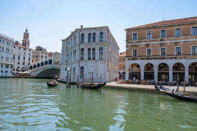 Boats in canal amidst buildings against clear sky