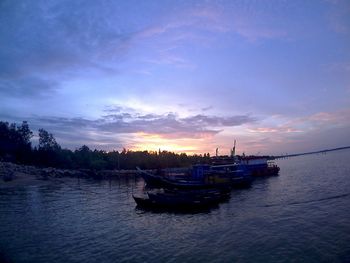 Boat moored in sea against sky during sunset