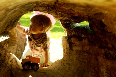 Boy seen through hollow log