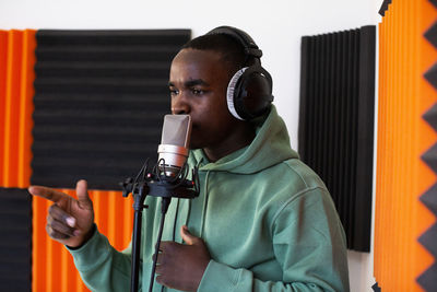 Young male rapper rapping on microphone while recording song in studio