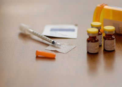 High angle view of syringe with medicines bottles on table in clinic