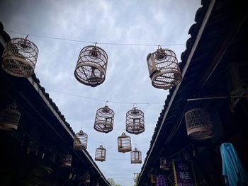 Low angle view of lantern hanging by building against sky