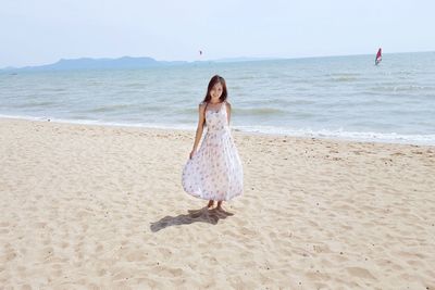 Portrait of young woman standing at beach against clear sky during sunny day