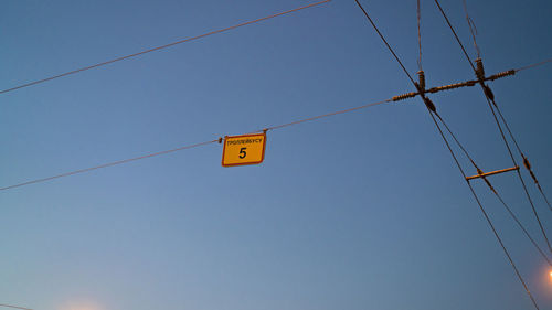 Low angle view of power lines against clear blue sky