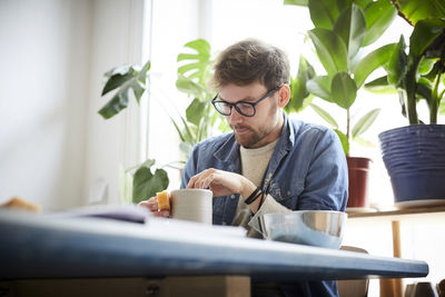 Young man making craft product in pottery class