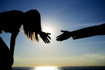 Silhouette hand against sky during sunset