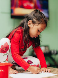 Girl looking away while sitting on table