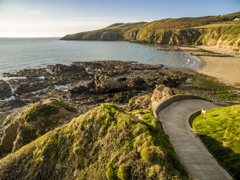 Scenic view of road by sea against sky