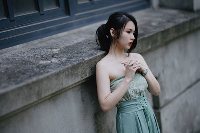 Young woman standing against wall