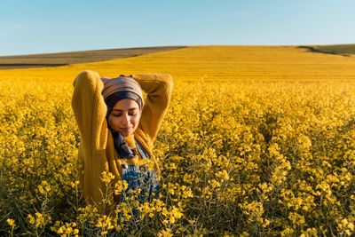 Young woman with yellow flowers in field
