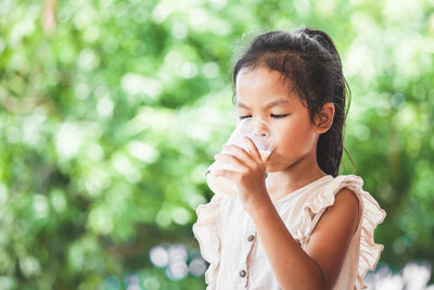 Close-up of girl drinking milk from glass outdoors