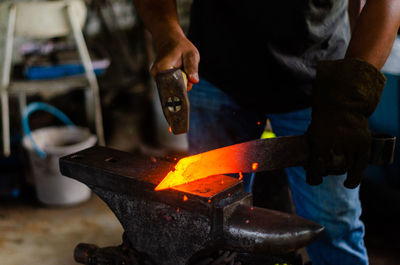 A blacksmith is hammering the hot red colour steel to make a knife