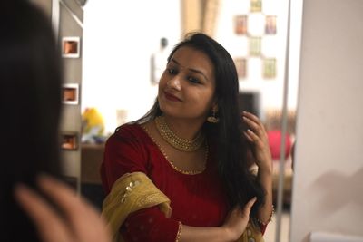 Smiling woman in traditional clothing standing in front of mirror