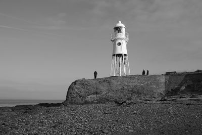 Lighthouse by sea against sky