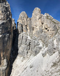 Low angle view of rocky mountains against blue sky