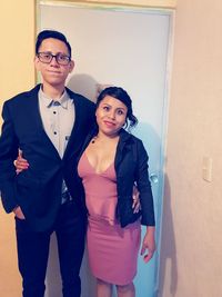 Portrait of young couple standing against wall