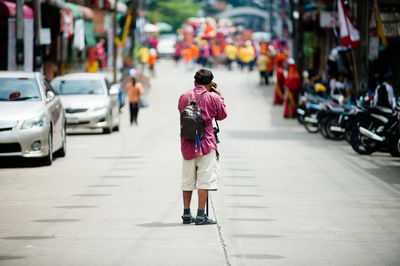 Rear view of man photographing on street