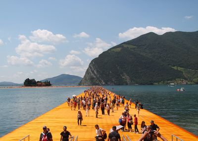 People swimming in sea against mountains