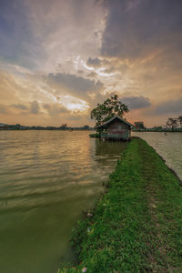 Scenic view of lake by building against sky during sunset
