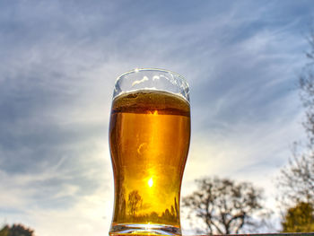 Close-up of beer glass against sky