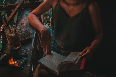 Midsection of woman reading book while sitting in cafe