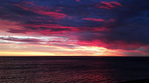 Scenic view of sea against moody sky during sunset