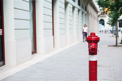 Fire hydrant on sidewalk against woman walking in background