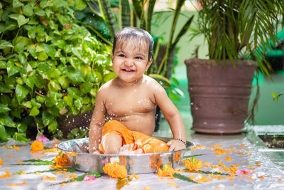 Cute toddler baby boy bathing in decorated bathtub at outdoor from unique perspective