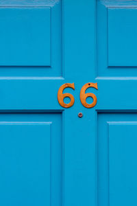 House number 66 on a blue wooden front door in london 