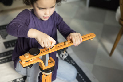 High angle view of girl playing with crane toy on floor at home