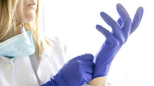 Medicine and surgery theme: female nurse putting on protective blue gloves