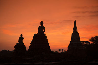 Low angle view of statues and temple at sunset
