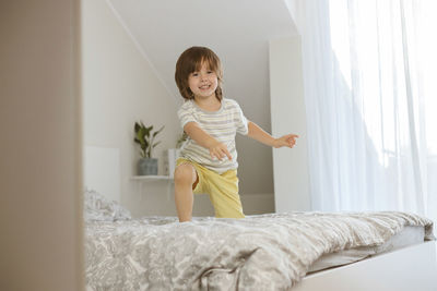 A little boy joyfully jumps on the bed in the bedroom. fun games at home. children's activity 