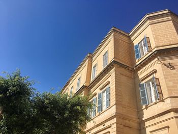 Low angle view of apartment building against clear blue sky