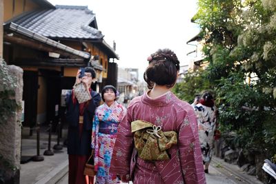 Rear view of people walking along buildings