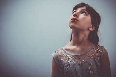 Portrait of a young woman looking away against wall