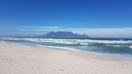 Scenic view of beach against blue sky