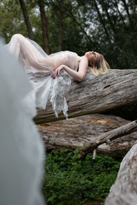 Woman lying on tree trunk in forest