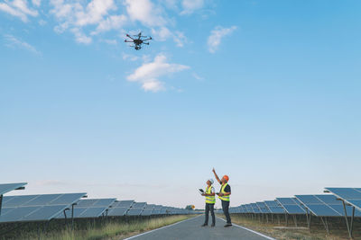 Man with umbrella standing against blue sky