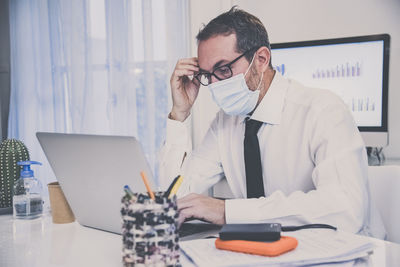 Business man with surgical masks working in the office during lockdown for coronavirus covid-19. 