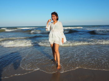 Full length of young woman standing on beach